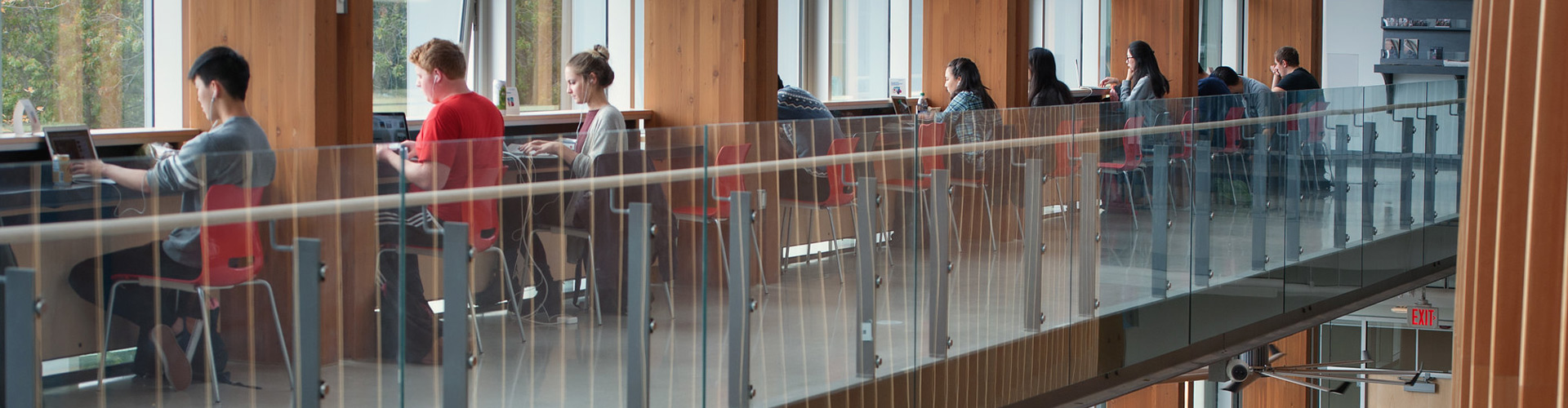 students in cubicle seating along building window on the upper floor